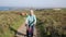 Active old lady pensioner walking towards camera with three wheel trolley mobility aid on coast path