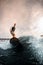 active one-armed sportsman standing on surfboard and rides the wave. Wakesurfing on the river