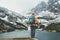 Active people in nature concept. Dressed bright orange jacket female backpacker enjoying the Velicke pleso mountain lake view as