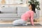Active pregnant black woman exercising at home, doing yoga
