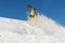 Active professional snowboarder in bright sportswear riding down a powder mountain slope