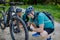 Active senior couple repairing bicycle, pumping up tire in nature in summer.