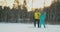 Active senior couple on skis moving down snowdrift in snowfall during training in winter forest