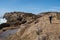 Active senior woman stands on the slippery rocks of Point Lobos State Reserve in California, admiring the scenery and taking