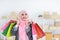 Active smart asian muslim woman in jean jacket standing and holding shopping bags with online package box delivery background.