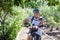 Active smiling senior woman cycling with her electro bike in a green park wearing helmet. Mature attractive woman stops using