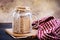 Active sourdough starter in glass jar. Rye leaven for bread on wooden cutting board and kitchen towel on brown background. Close-