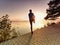 Active sport man runner stretching body on pavement lake side