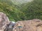 Active sporty woman relaxing in nature, practicing yoga on high clif by 500 feet waterfall at Black river gorges