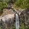 Active sporty woman relaxing in nature, practicing yoga on high clif by 500 feet waterfall at Black river gorges