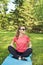 Active sporty woman sitting on a sport mat and relaxing after training outdoors