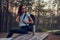 Active student is checking time on her watch while sitting on the table in the middle of the forest.