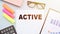 ACTIVE. Text on office desk with calculator, markers, glasses and financial charts