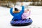 Active toddler girl and school boy sliding together down the hill on snow tube. Children, siblings having fun outdoors