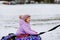 Active toddler girl sliding down the hill on snow tube. Cute little happy child having fun outdoors in winter on sledge