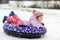 Active toddler girl sliding down the hill on snow tube. Cute little happy child having fun outdoors in winter on sledge