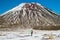 Active volcanic mountain Mt. Ngauruhoe and adventurous mountain hiker back view with backpack, Tongariro crossing