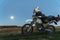 Active way of life, enduro motorcycle, a guy looks at the stars at night and the moon, unity with nature, the spirit of adventure