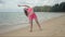 Active woman in pink swimsuit making workout on beach