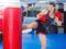 Active woman practicing with punching bag in box gym