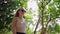 Active woman in sunglasses enjoys nature walk in lush forest, breathing fresh air. Independent traveler female explores