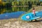 Active woman with SUP board near beautiful lake, nature on background, stand up paddling water adventure outdoors