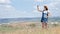 Active woman tourist with backpack taking selfie in the field using smartphone