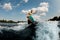 Active woung woman wakesurfer skilfully jumping with wakeboard at splashing river wave