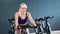 Active young blonde fitness woman spinning pedal on exercising bike. Shot with RED camera in 4K