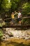 Active young cople hiking on a wooden brifge over mountain creek