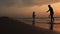 Active young dad and daughter playing beach tennis game in sunset light