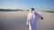 Active young male emirate Arabian UAE Sheikh rejoices in life and walks through expanses of desert on clear evening.
