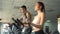 Active young man and woman using elliptical machine