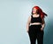 Active young plus-size woman with flowing red hair in black sport top and leggings shouting with laughter and delight