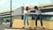 Active young skaters couple learn to ride longboard together hold hands laughing stand on skateboard