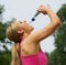 Active young woman drinking water after exercise