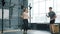 Active young woman jumping with skipping rope training with male trainer in gym