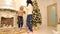 Active young women having fun and dancing in bright living room with festive fireplace decorated with festive Christmas
