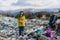 Activist with gas mask and plant standing on landfill, large pile of waste, environmental concept and eco activism.