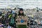 Activist holding placard, protest sign, standing on landfill, large pile of waste on sea shoreline, environmental