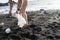 Activist woman picking plastic garbage and hold bag in the beach with bikini. Environmental solution. Volunteer reduce the trash