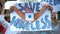 Activists with Save homeless poster chanting to support migrants, refugee rights