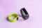Activity smart trackers on light pink background. Black and green fitness health watch with shadow of palm leaf, sport bracelets