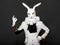 Actor posing in white rabbit suit on black