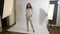 Actress elegant dressed in white posing in a studio with hands in her pocket and hair on one side for photographer -