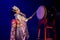 Actress in white traditional japanese stage costume komono hits the drum