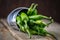 Acute green peppers in an aluminum bucket on old boards