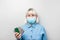 Acute viral respiratory infections. Adult woman in a blue shirt and mask holds pills in hands on a gray background with