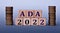 ADA 2022 - acronym on wooden cubes on a light background with coins