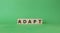 Adapt symbol. Concept word Adapt on wooden cubes. Beautiful green background. Business and Adapt concept. Copy space